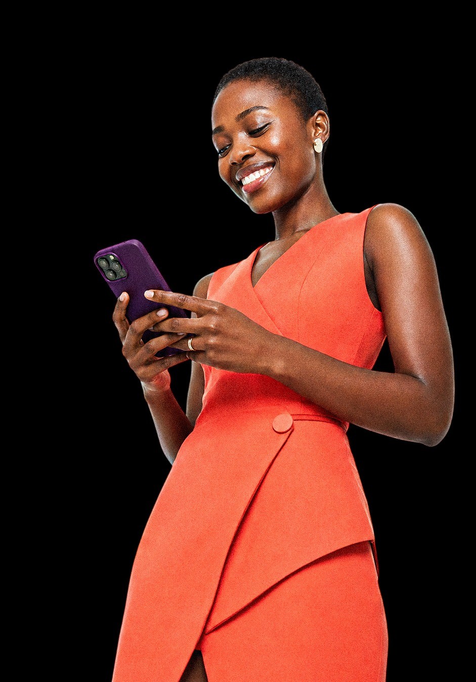 Smiling woman in a coral dress using her phone