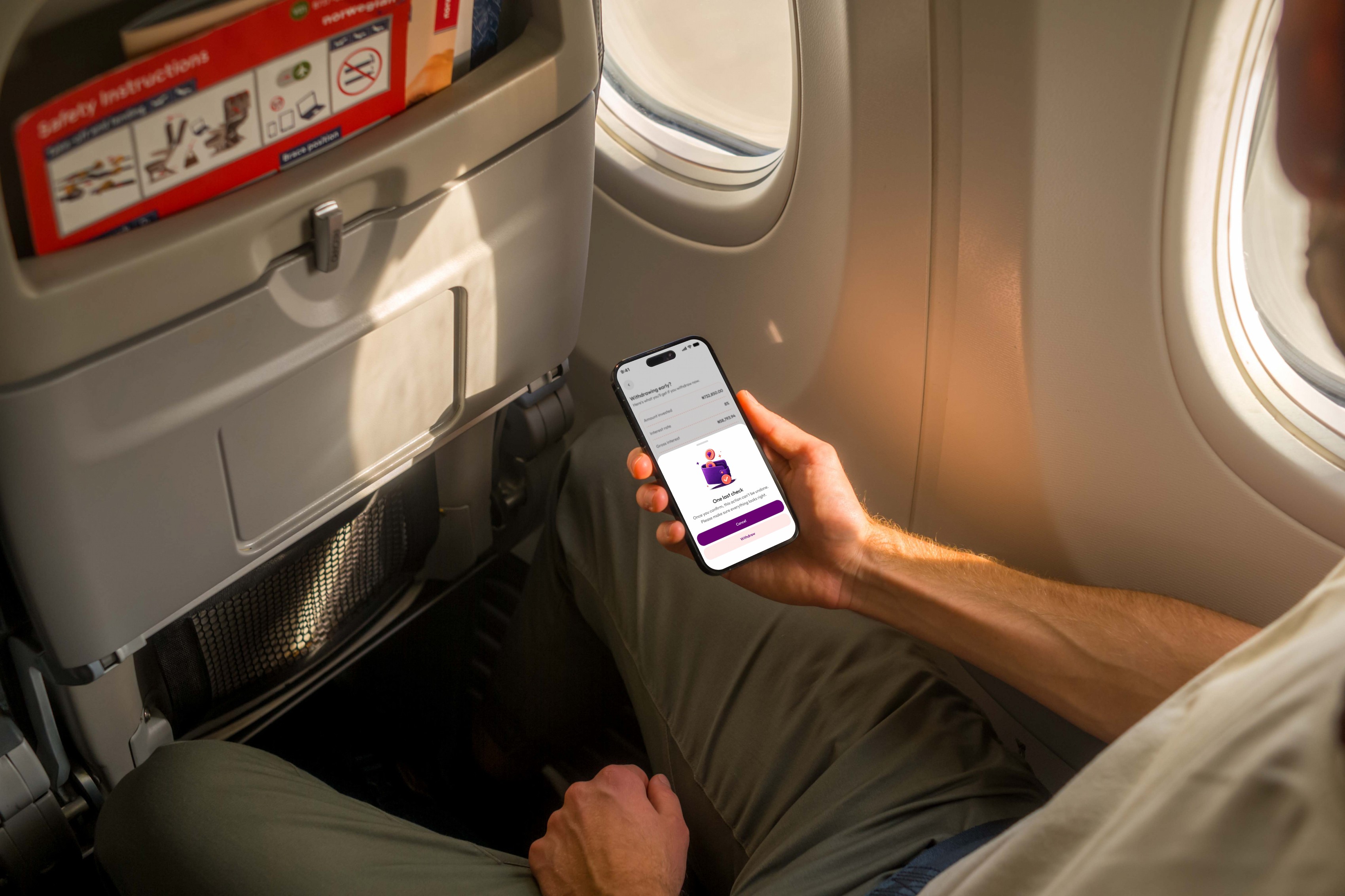 Hand holding a phone with the Kivo early withdrawal screen on a plane