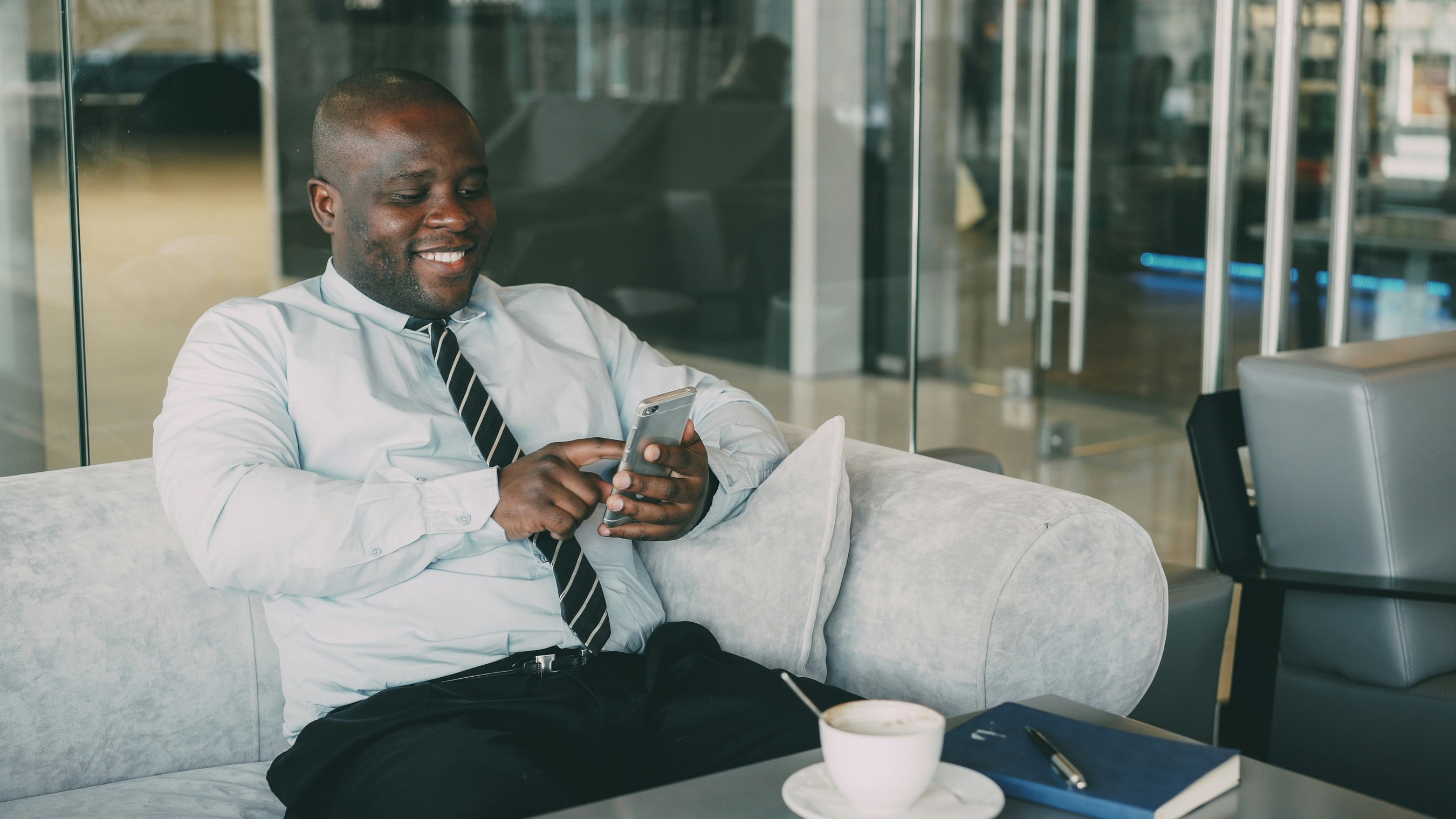 Man smiling while using his laptop in an office lounge